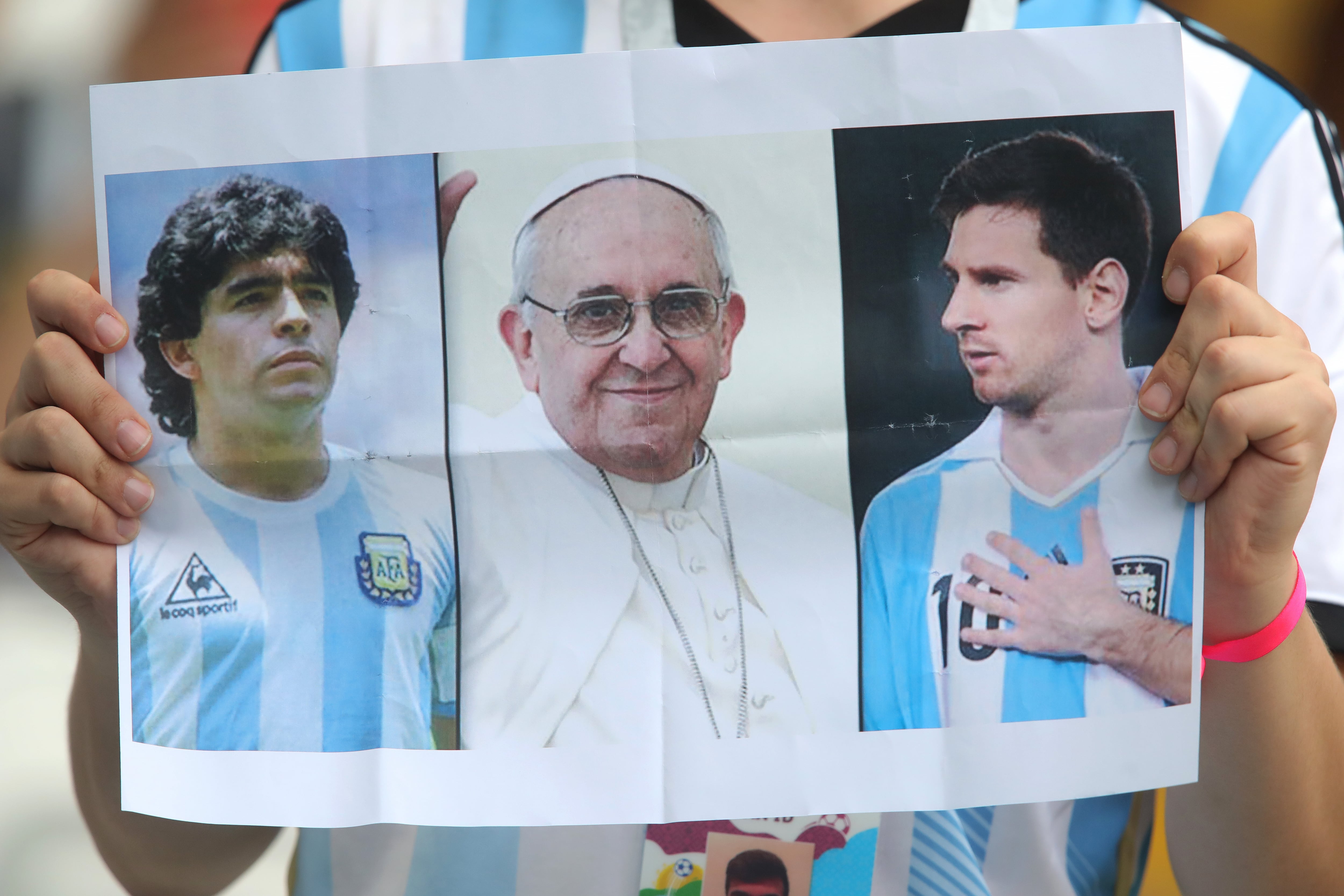 Un seguidor argentino muestra la imagen de Diego Armando Maradona, el papa Francico y Lionel Messi